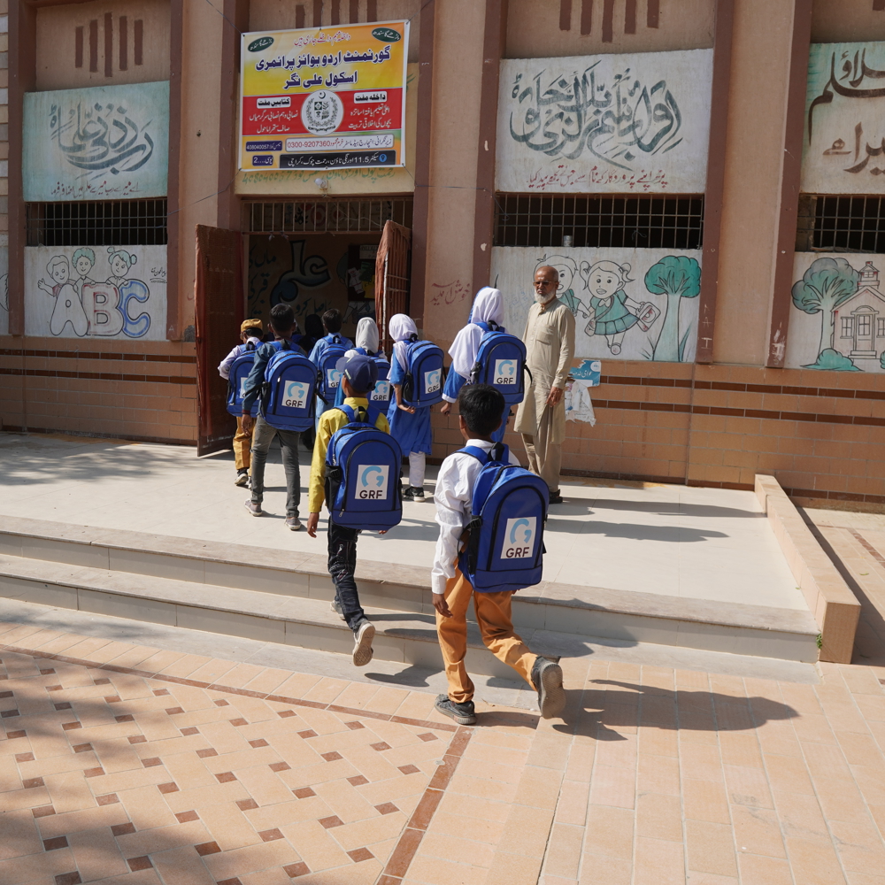 children in Pakistan walking wearing blue school bags from GRF