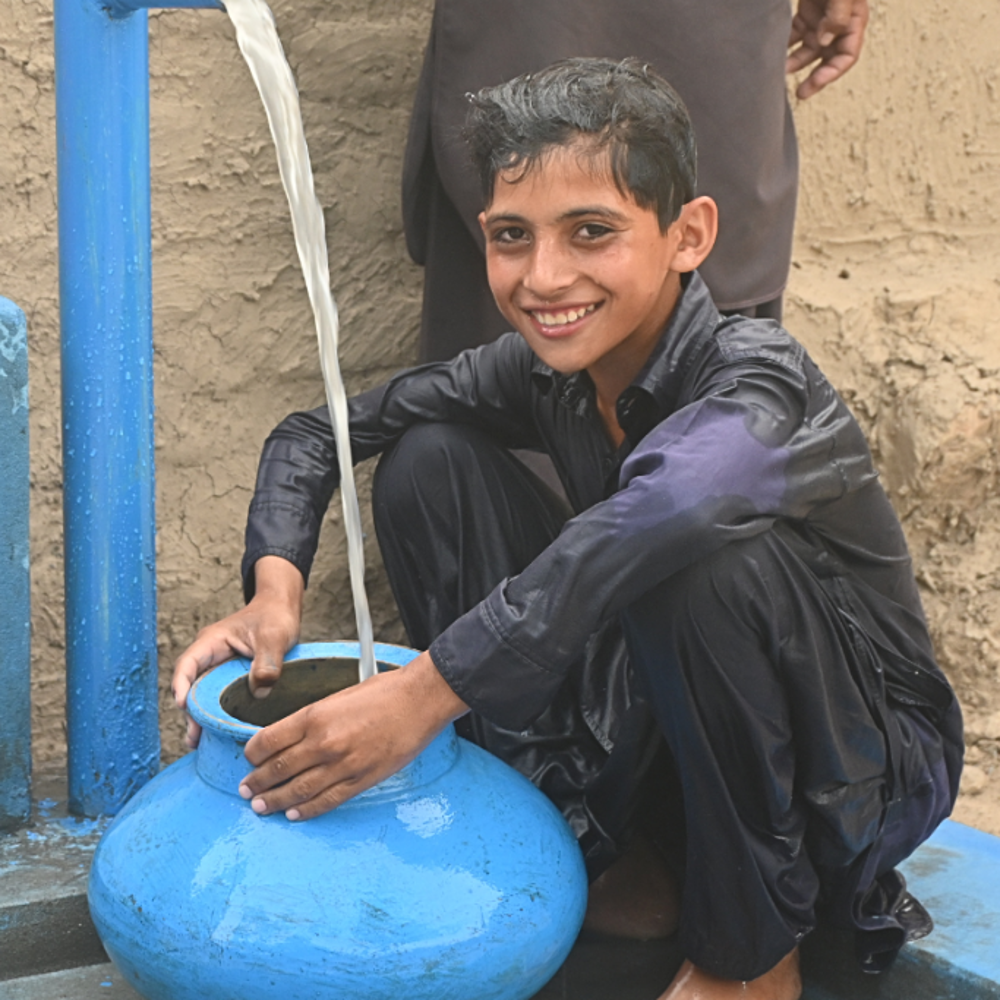 child smiling as he uses GRF Pakistan water pump