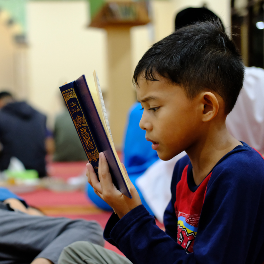 young boy reading the Quran