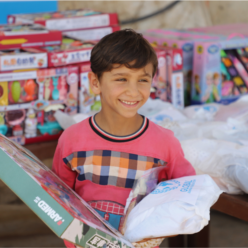 child smiling holding Eid gifts from GRF